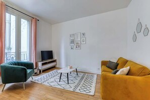 A living room with a sofa, a coffee table, and a TV on a stand. - Poissonnière – Cosy Apartment near Montmartre (Paris)