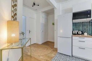 A modern kitchen with white cabinets, a built-in microwave, and a coffee maker on the countertop. - Poissonnière – Cosy Apartment near Montmartre (Paris)