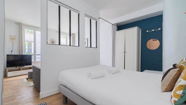 A bedroom with a bed, a TV, a wardrobe, and a mirror. - Greneta - Spacious Flat Montorgueuil 4PAX (Paris)