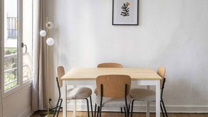 A dining area with a wooden table and four chairs, a framed artwork on the wall, and a floor lamp. - Greneta - Spacious Flat Montorgueuil 4PAX (Paris)