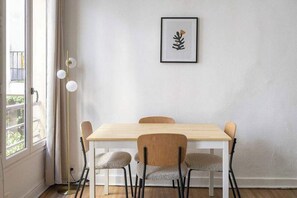 A dining area with a wooden table and four chairs, a framed artwork on the wall, and a floor lamp. - Greneta - Spacious Flat Montorgueuil 4PAX (Paris)
