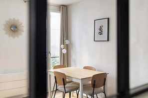 A dining area with a table and chairs, a framed artwork on the wall, and a sunburst decoration. - Greneta - Spacious Flat Montorgueuil 4PAX (Paris)