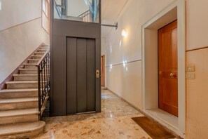 A hallway with a marble floor, a wooden door, and a staircase with a metal railing. - An elegant and bright 56 ​​square meters apartment featuring a spacious patio (24 square meters)—perfect for four guests—located on the raised ground floor of a renovated building.The property is ideally situated for visiting Venice and is well-s (Venice)