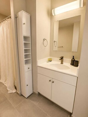A bathroom with a tall cabinet, a sink with a mirror, and a towel rack. - Modern 2BR in Heart of Philly | Rafa Properties (Philadelphia)