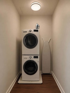 A laundry room with two stacked front-loading washing machines and a tall, white, floor-standing dryer. - Spacious 2BR Center City Gem | By Rafa Properties (Philadelphia)