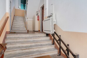 Una escala amb barana, un extintor i una porta a dalt.