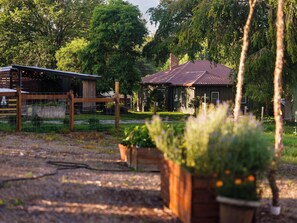 Ein rustikales Gebäude mit einer Metallbedachung, umgeben von Grünflächen und einer Umzäunung.