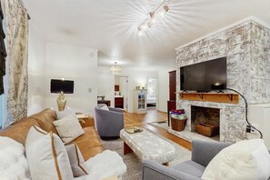 A living room with a fireplace, a television mounted on the wall, a sofa, and a coffee table. - Dog-friendly farm cottage with patio, walk to dining & Ecusta Trail, ac (Horse Shoe)