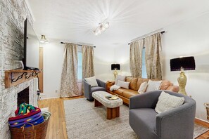 A living room with a fireplace, a sofa, a coffee table, and a television. - Dog-friendly farm cottage with patio, walk to dining & Ecusta Trail, ac (Horse Shoe)