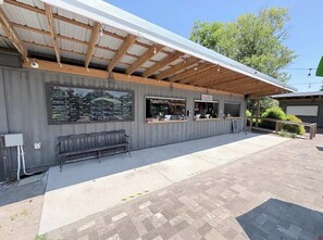 A covered outdoor seating area with a chalkboard menu, a bench, and a small storefront. - Dog-friendly farm cottage with patio, walk to dining & Ecusta Trail, ac (Horse Shoe)