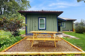 A small, single-story building with a green exterior and a wooden picnic table in front. - Dog-friendly farm cottage with patio, walk to dining & Ecusta Trail, ac (Horse Shoe)
