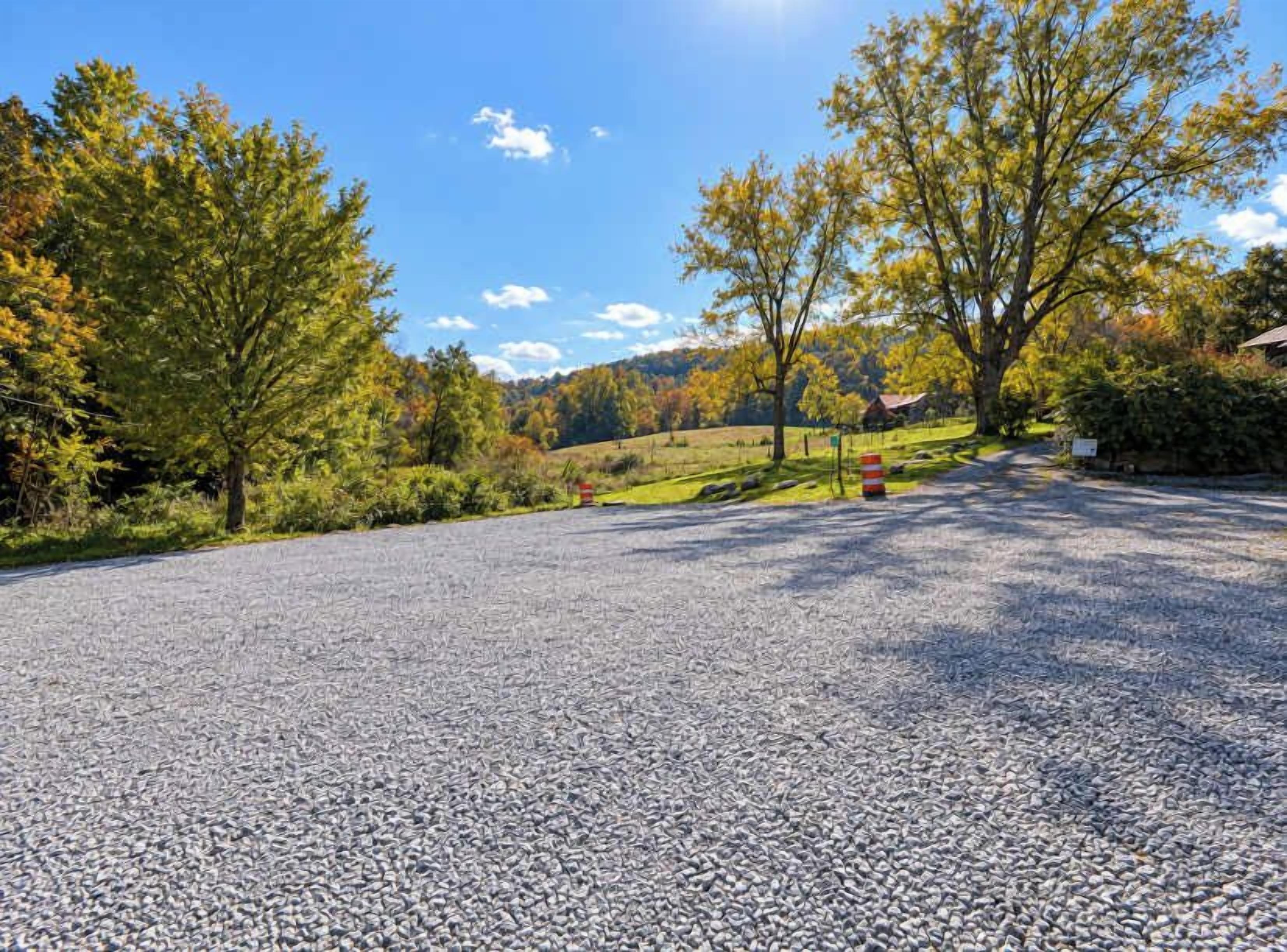 Ein Kiesweg führt zu einem Gebäude, im Hintergrund blauer Himmel und Bäume.
