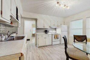A kitchen with white cabinets, a stainless steel sink, a stove, and a refrigerator. - Dog-friendly farm cottage with patio, walk to dining & Ecusta Trail, ac (Horse Shoe)