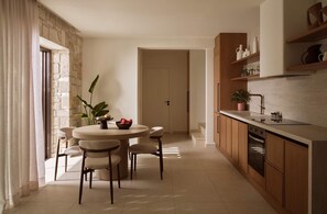 A modern kitchen with a dining area, stone wall, and wooden cabinets. - Villa Aelionis, Private Pool, Furnished Terrace, Zakynthos (Zakynthos)