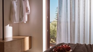 A bedroom with a wooden bedside table, a bed with a brown knitted blanket, a tray with fruits and a pomegranate, and a view of trees through sheer curtains. - Villa Aelionis, Private Pool, Furnished Terrace, Zakynthos (Zakynthos)