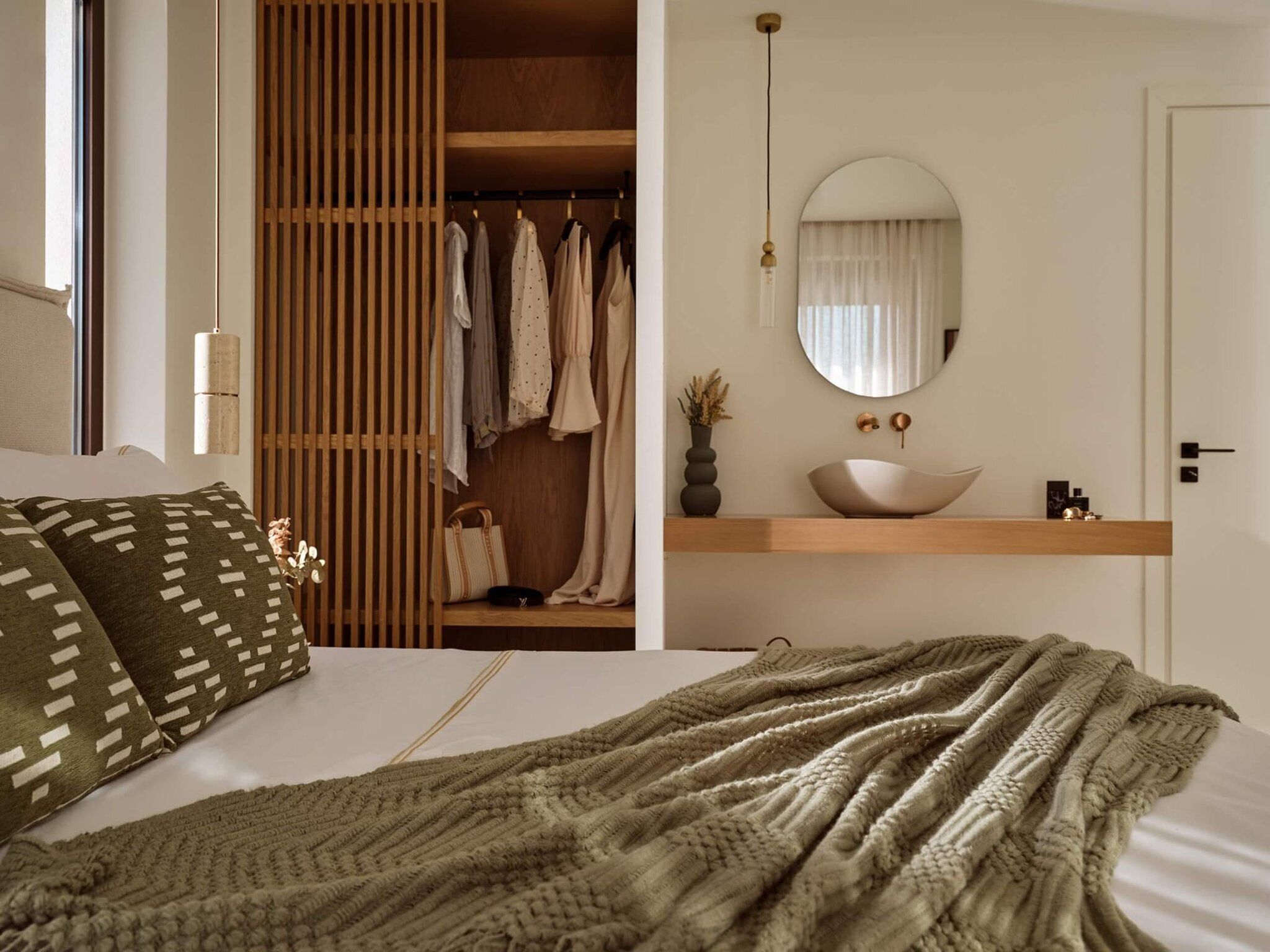 A bedroom with a bed, a wardrobe, a mirror, and a bedside table.