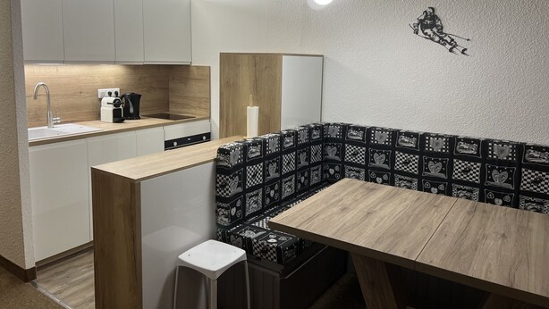 Een moderne keuken met witte kasten, een houten aanrecht en een bankje met zwart-wit patroon.