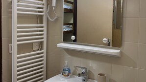 Een badkamer met een witte wastafel, een spiegel, een handdoekhouder en een haardroger.