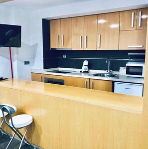 Una cucina moderna con mobili in legno, forno a incasso e microonde.
