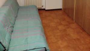Una stanza con un letto, un termosifone, una finestra con tende e un armadio.
