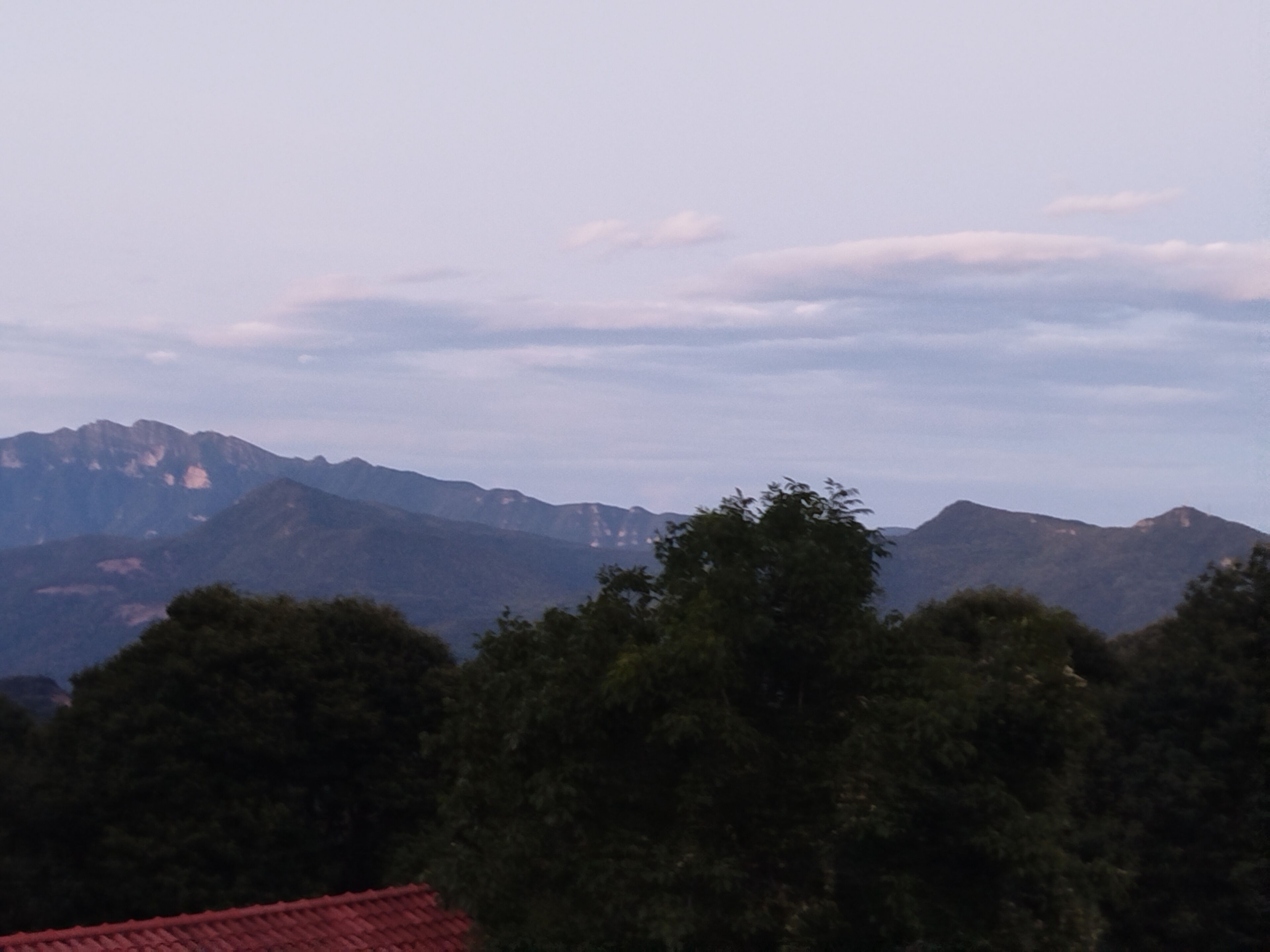 A mountain range with a red-roofed building in the foreground.