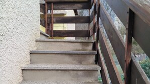 Una serie di gradini in cemento con una ringhiera in legno che conduce a un edificio con facciata gialla.