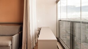 A modern interior with a long white table, a sofa, and a view of a cityscape through large windows. - Arapanes by Bhomy (São Paulo)