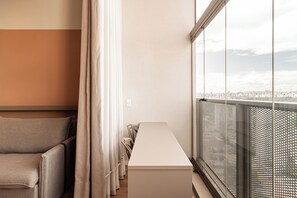 A modern interior with a long white table, a sofa, and a view of a cityscape through large windows. - Arapanes by Bhomy (São Paulo)