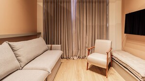 A modern room with a sofa, a chair, and a flat-screen TV mounted on the wall. - Arapanes by Bhomy (São Paulo)