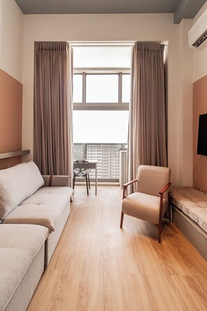 Une chambre d’hôtel avec un canapé, un fauteuil et une petite table.