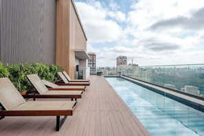 A rooftop pool area with lounge chairs and a city view. - Arapanes by Bhomy (São Paulo)