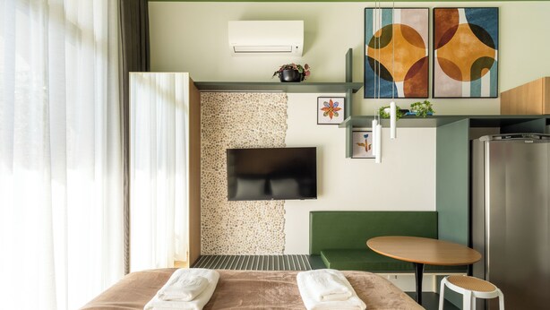 A hotel room with a bed, a TV, a small table, a sofa, and a refrigerator. - Arapanes by Bhomy (São Paulo)