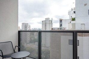 A balcony with a mesh railing, a metal chair, and a small table. - Arapanes by Bhomy (São Paulo)
