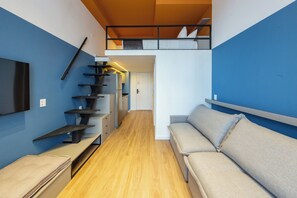 A compact living space with a sofa, a TV, a staircase, and a bunk bed. - Arapanes by Bhomy (São Paulo)