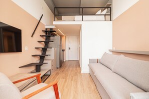 Een modern interieur met een trap, een bank en een flatscreen televisie.