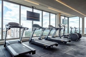 A gym with treadmills, stationary bikes, and a TV screen. - Arapanes by Bhomy (São Paulo)