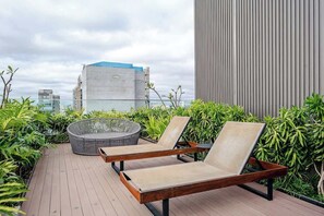 Een terras op het dak met lounge stoelen, een vuurkorf en uitzicht op de stadshemel.