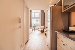 A modern kitchen with a refrigerator, a stove, and a dining area with a chair and table. - Arapanes by Bhomy (São Paulo)