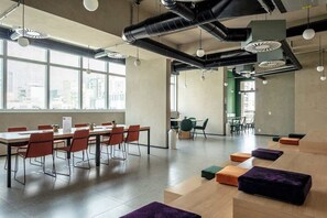 Ein modernes Interieur mit einem langen Tisch und Stühlen, einer grünen Wand und Blick durch große Fenster.