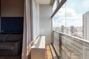 A balcony with a city view, a sofa, and a table. - Arapanes by Bhomy (São Paulo)