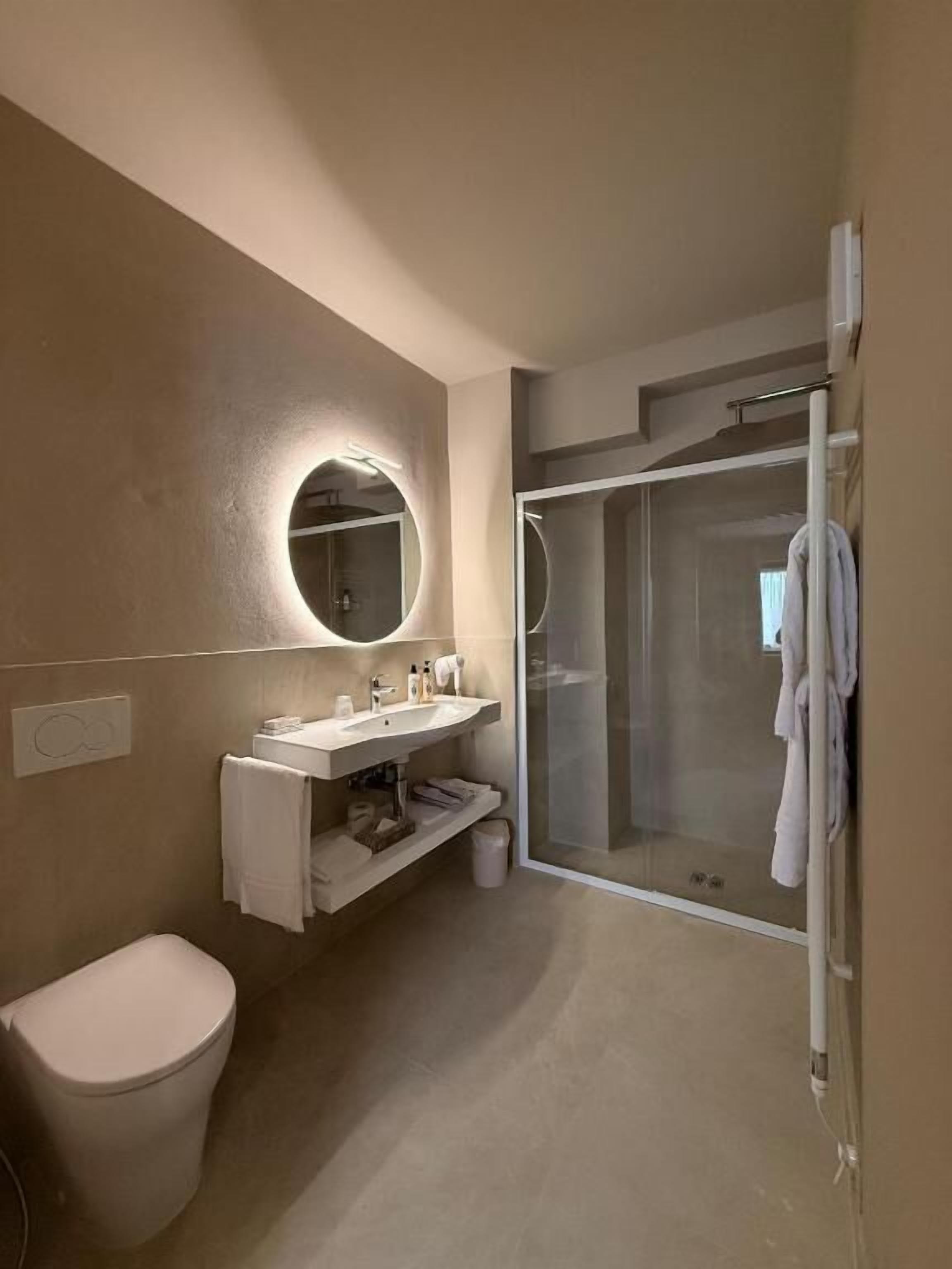 Un bagno moderno con WC, lavabo, specchio e cabina doccia in vetro.