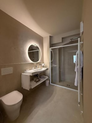 Ein modernes Badezimmer mit Toilette, Waschbecken, Spiegel und Duschkabine.
