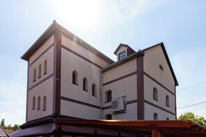 Un edificio de varios pisos con fachada simétrica, destacando una sección central con ventanas arqueadas y una sección más pequeña con un ventanucci.