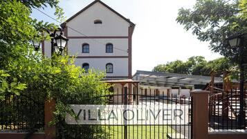 Villa Oliver with a gated entrance, a white building with a red roof, and a clear sky.