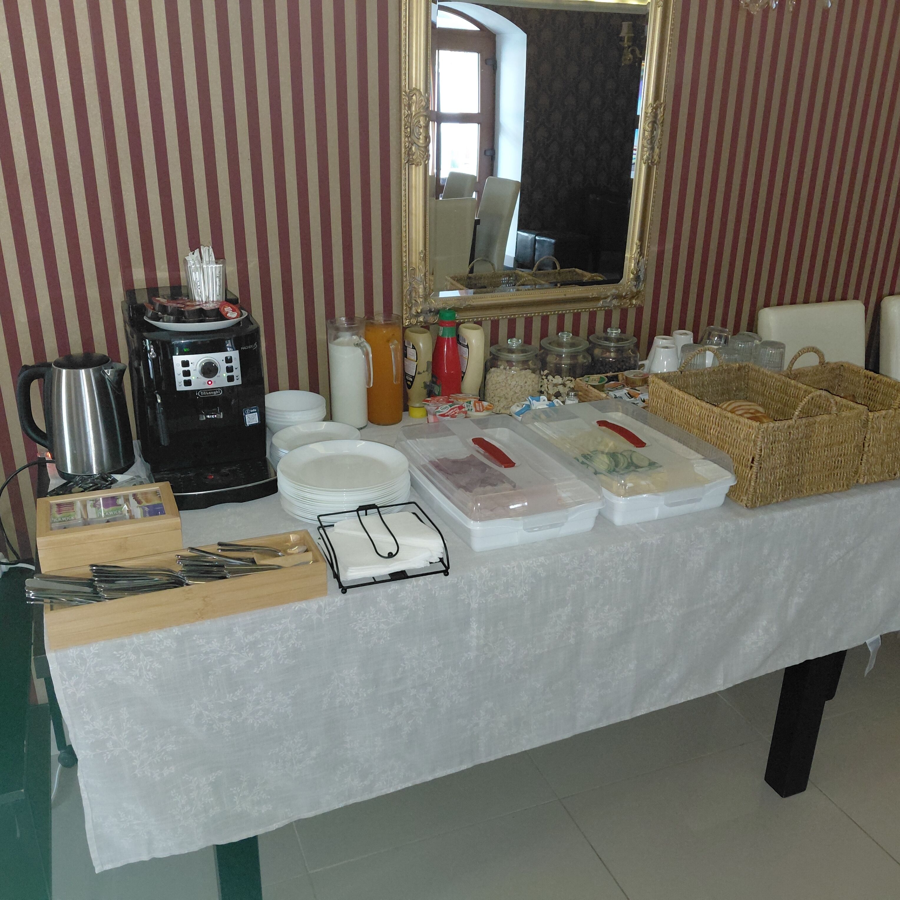 Ein reichhaltiges Buffet mit Kaffeemaschine, Tellern, Besteck und Speisebehältern.