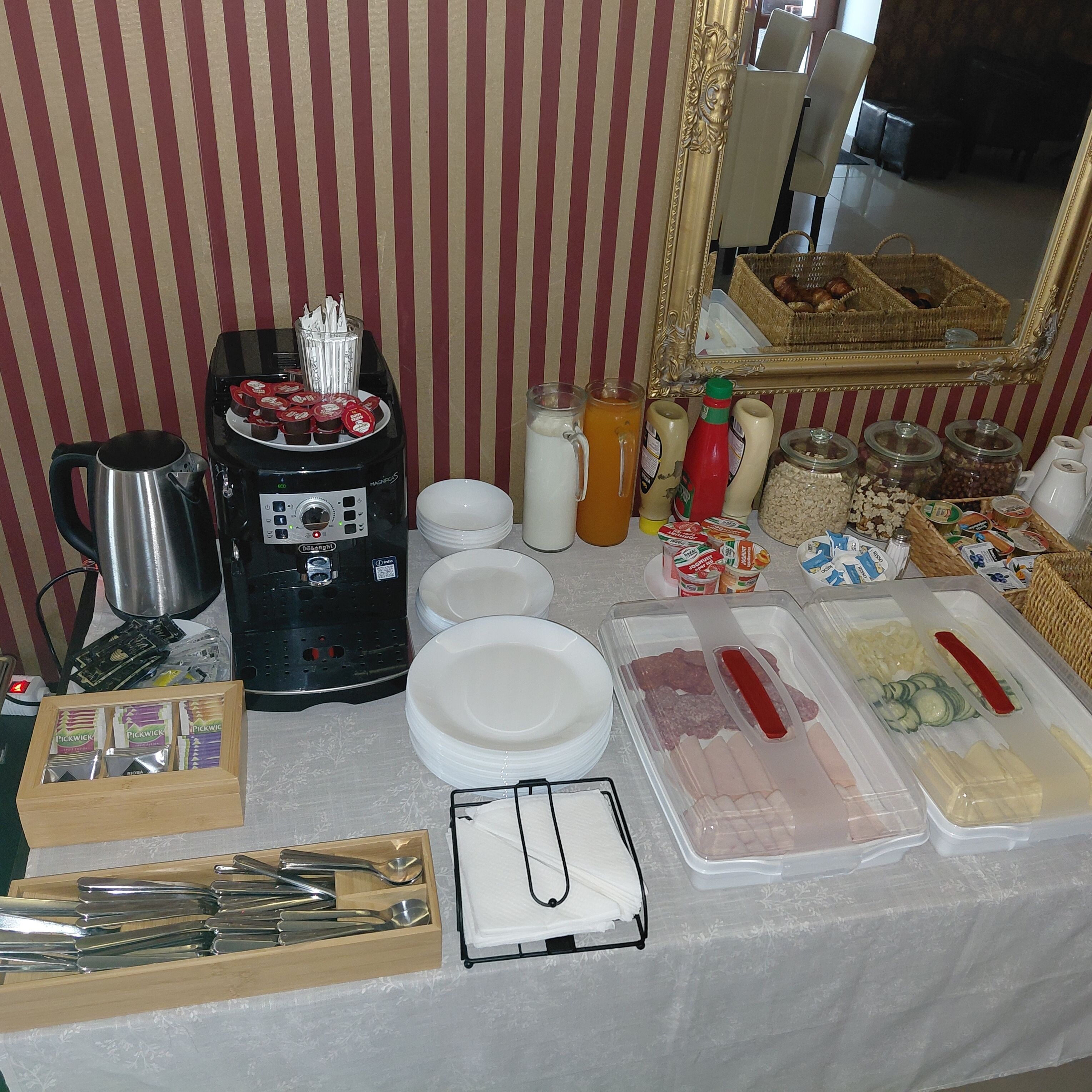 A buffet setup with a coffee machine, condiment bottles, and food containers.