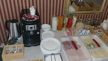 A buffet setup with a coffee machine, condiment bottles, and food containers.