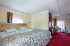 Une chambre d’hôtel avec un grand lit, une chaise, une petite table et une fenêtre avec des rideaux.