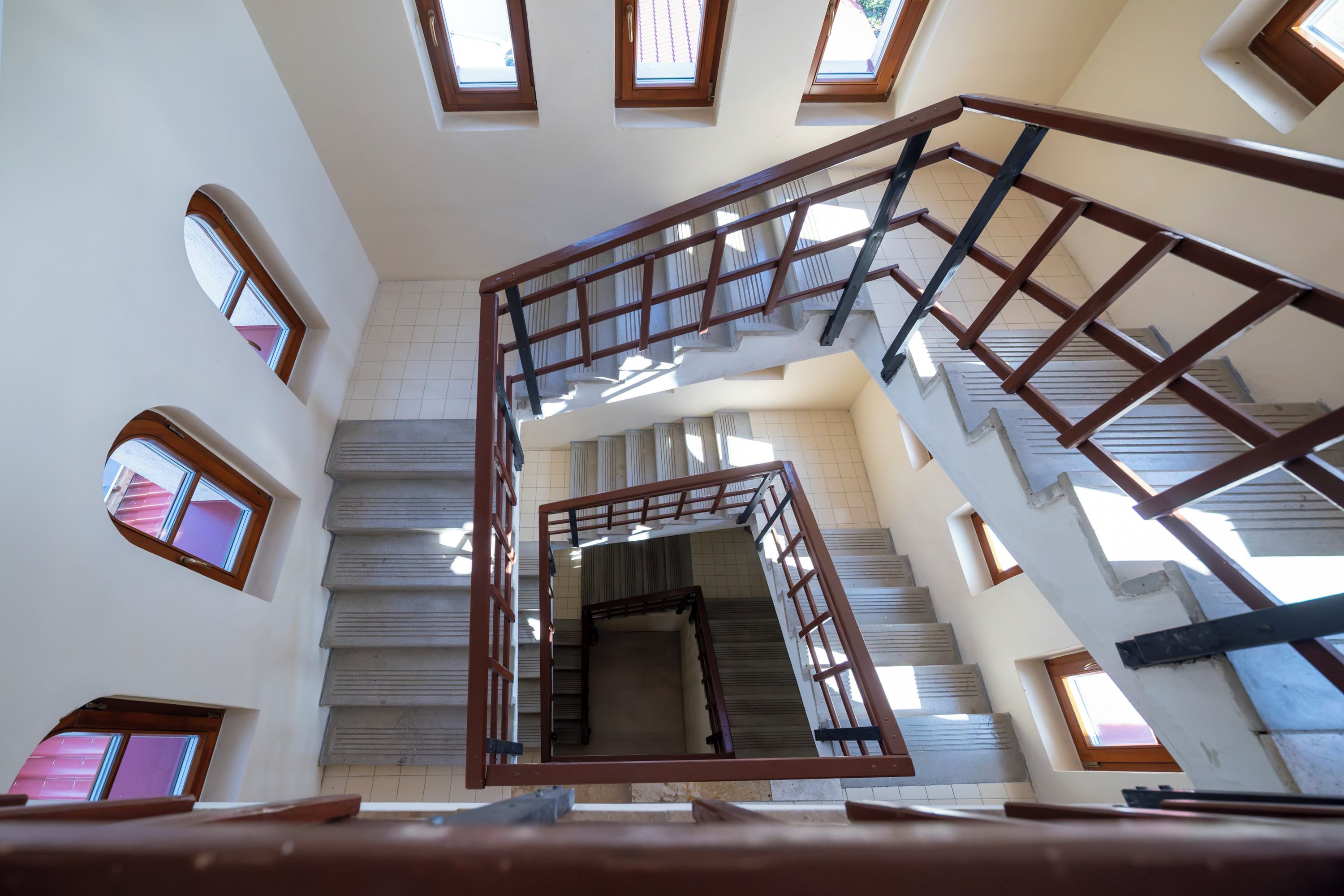 A multi-level interior with a central staircase, multiple windows, and a tiled floor.