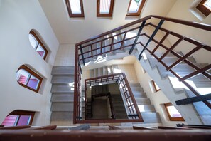 A multi-level interior with a central staircase, multiple windows, and a tiled floor. - Villa Oliver Abádszalók (Abádszalók)